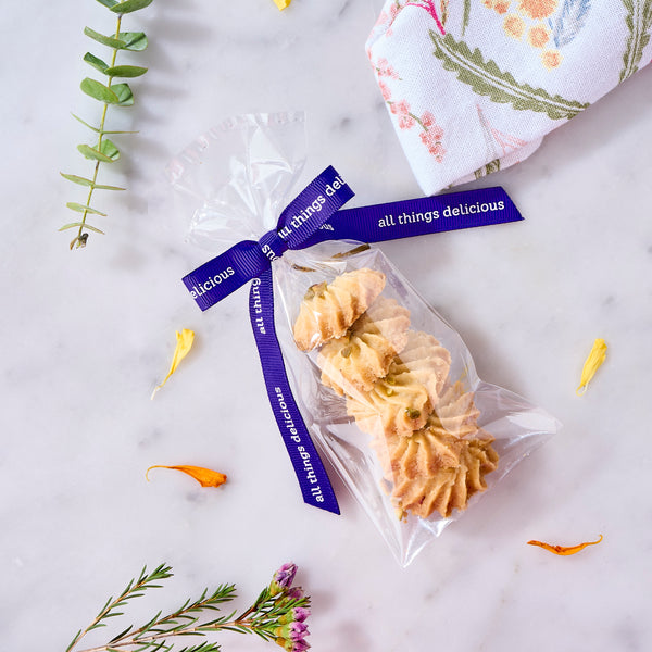 Halal Rasmalai Pistachio Cookie Gift Pack: piped eggless cookies in a clear bag tied with purple ribbon