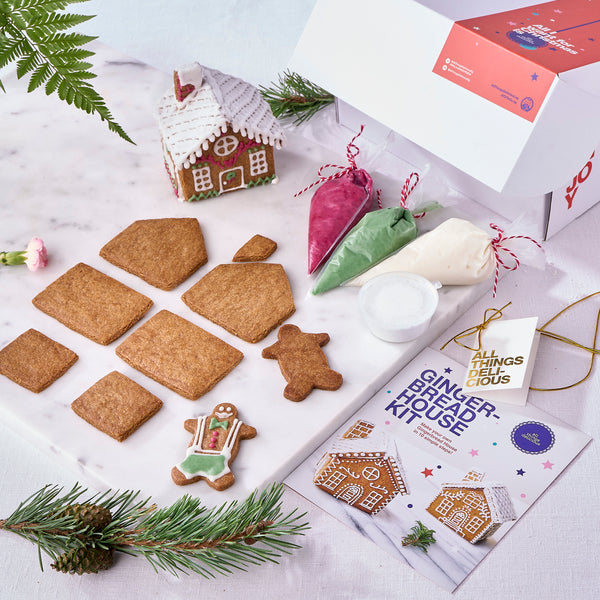 Christmas gingerbread house kit laid out with panels, icing bags and snow powder