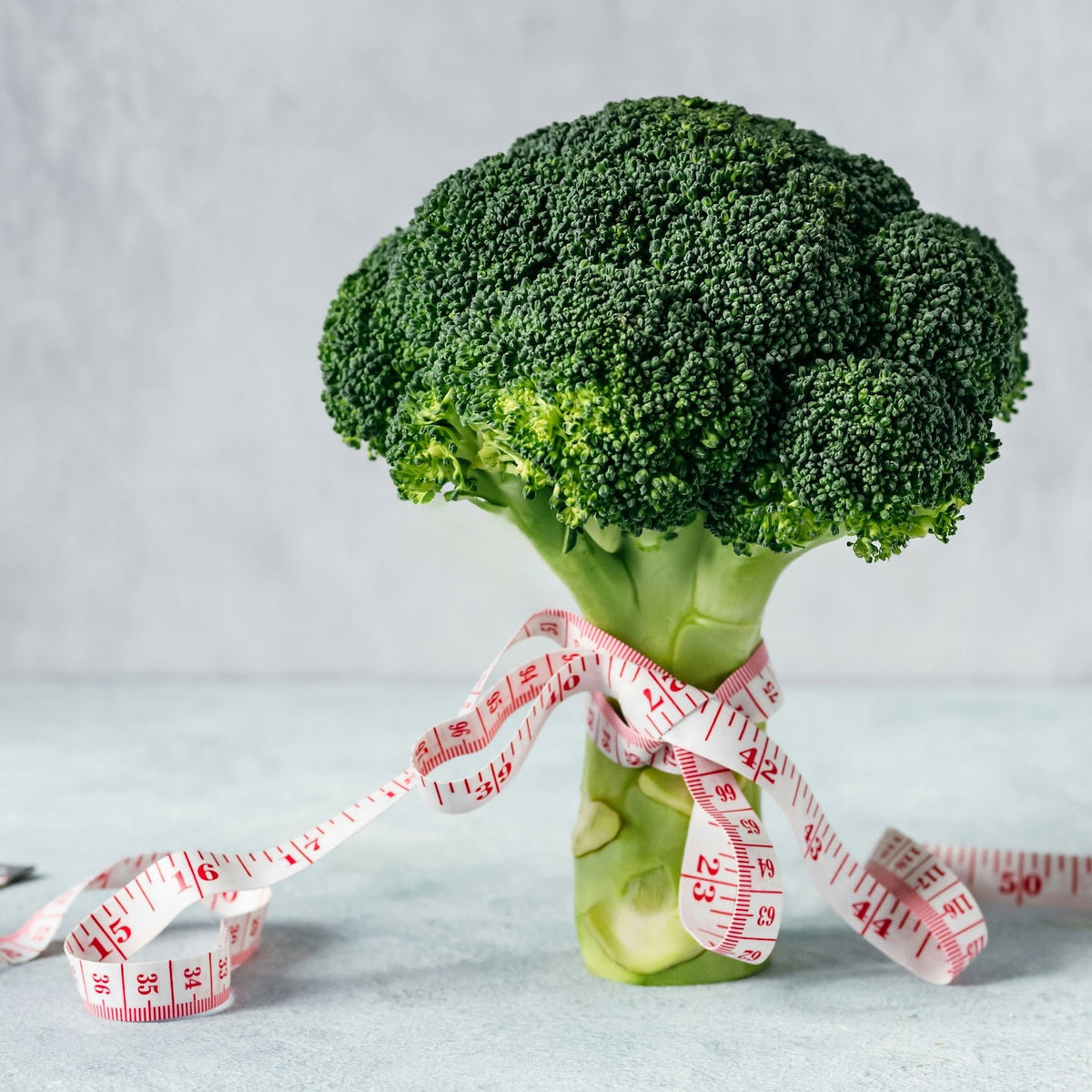 Head of broccoli tied with a tape measure, illustrating the switch to a healthier vegetarian diet