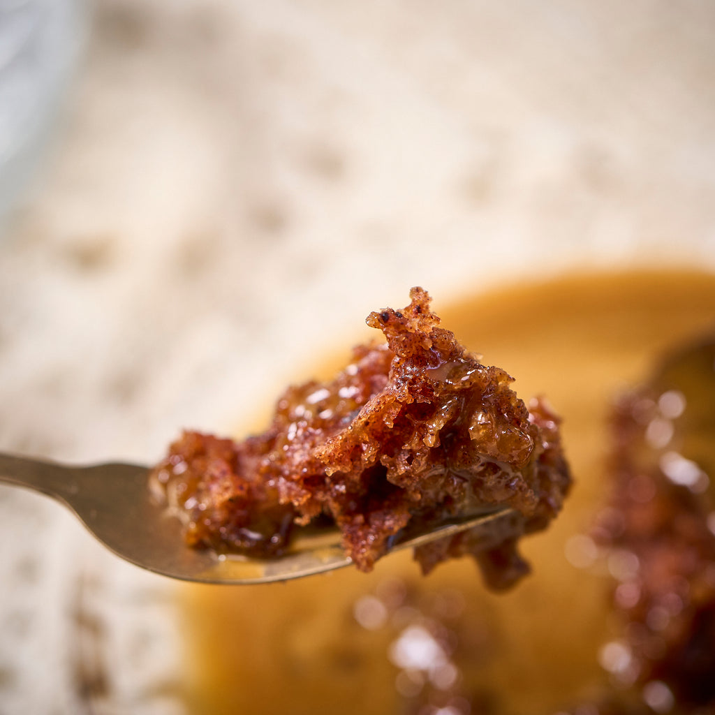 Halal Sticky Toffee Pudding on a fork, showing the moist date sponge soaked in toffee sauce