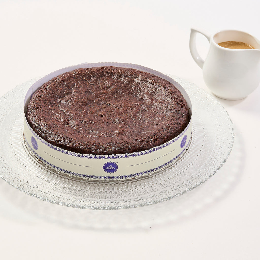 Halal Sticky Toffee Pudding, a whole sticky date sponge in a branded collar, with a jug of toffee sauce