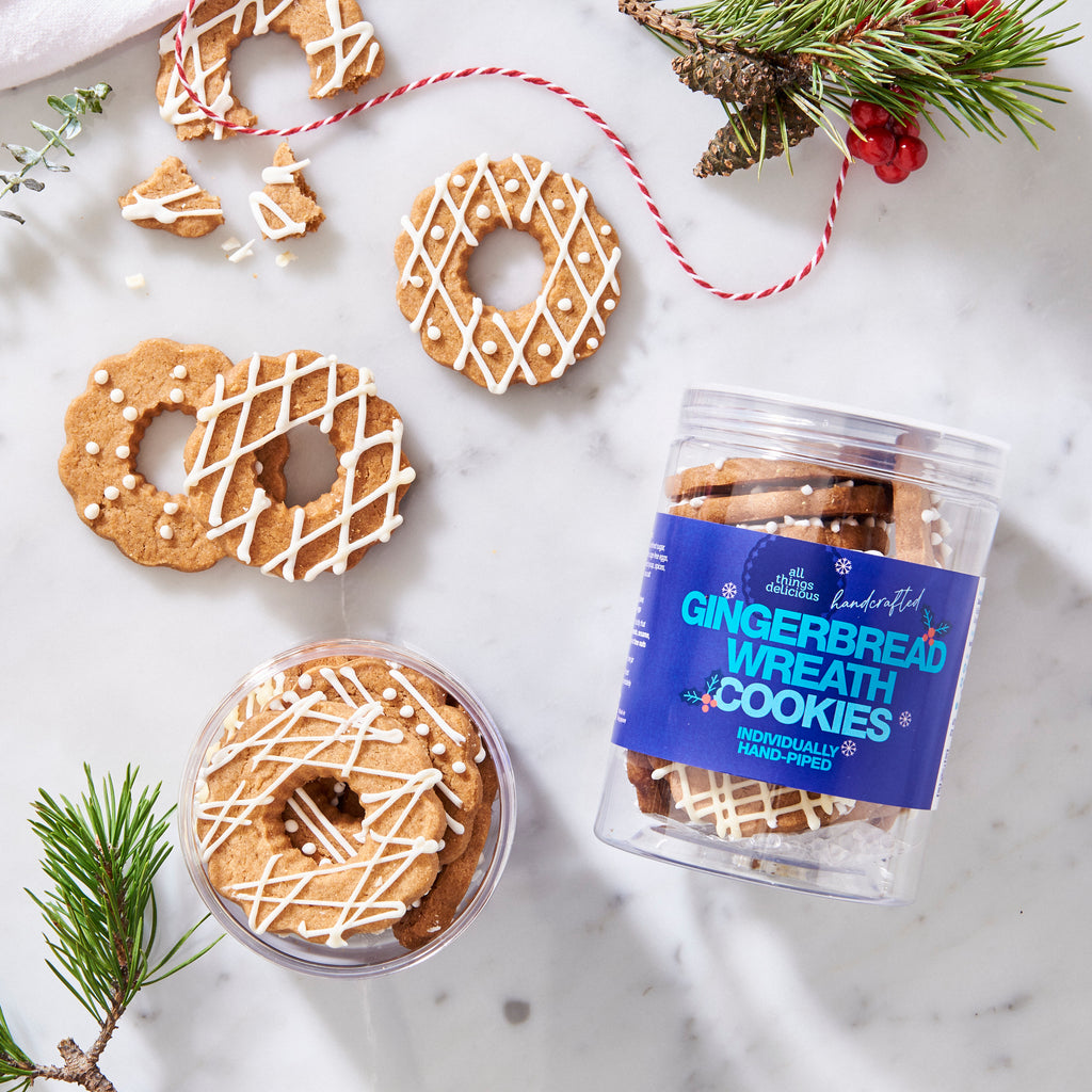 Christmas gingerbread wreath cookies piped with white icing, beside a labelled jar