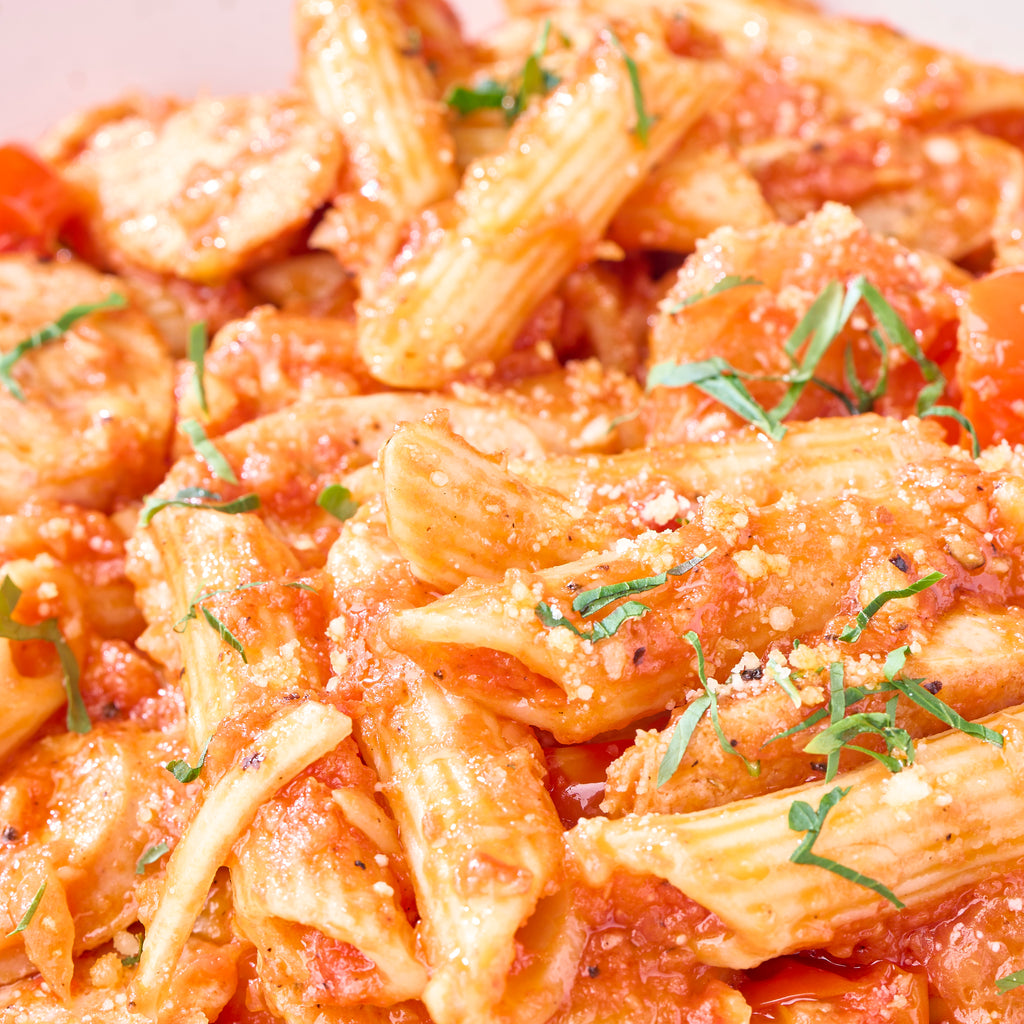 Close-up of penne in crushed cherry tomato sauce with fennel chicken sausage, parmesan and herbs