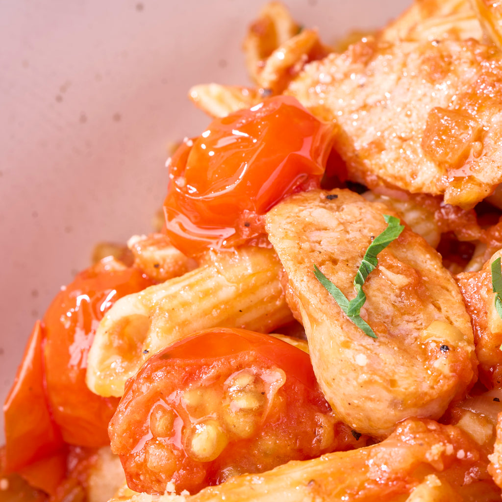 Close-up of blistered cherry tomatoes and sliced fennel chicken sausage tossed through penne