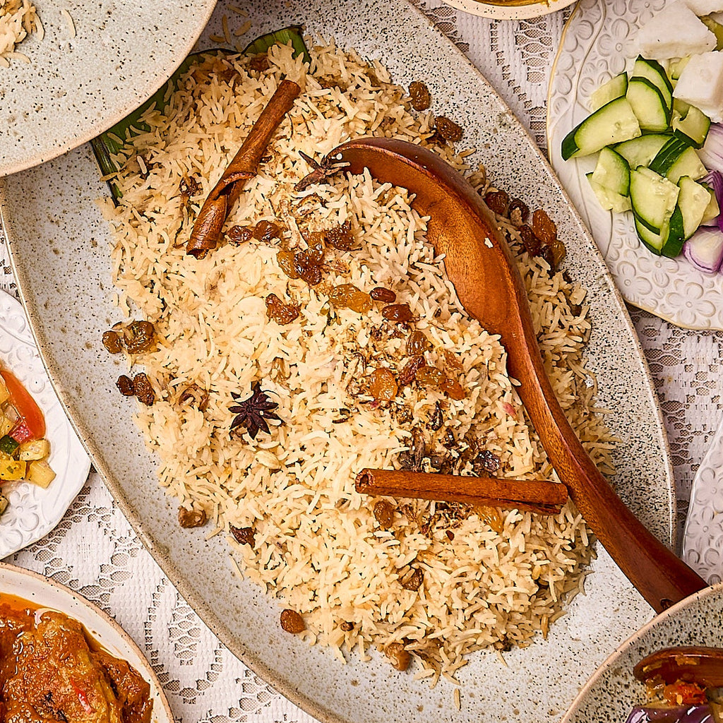 Halal Nasi Minyak spiced ghee rice with raisins, cinnamon sticks and star anise on a speckled platter