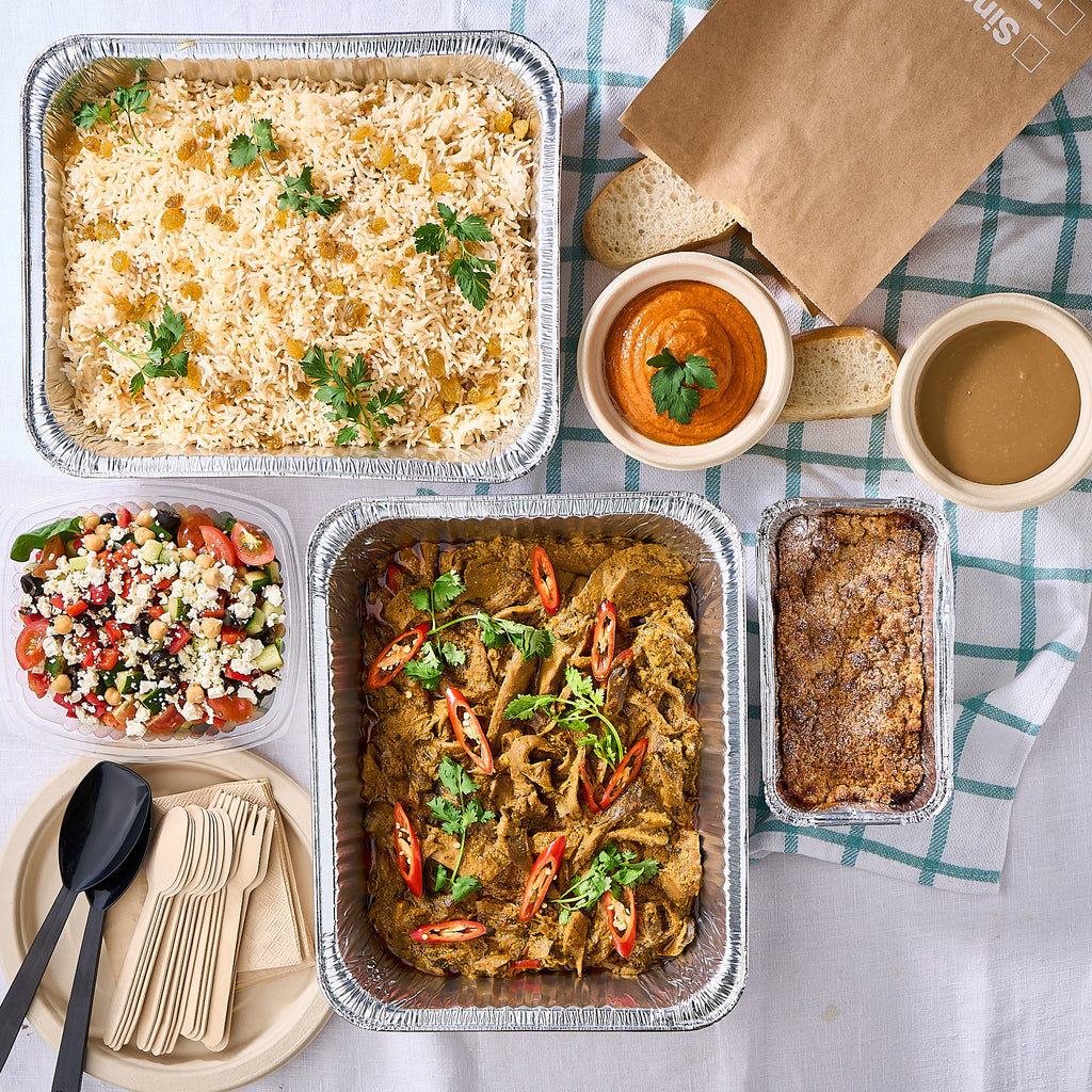Vegetarian mini buffet in takeaway trays: mushroom curry, basmati pilaf, chickpea salad, muhammara with bread and crumble