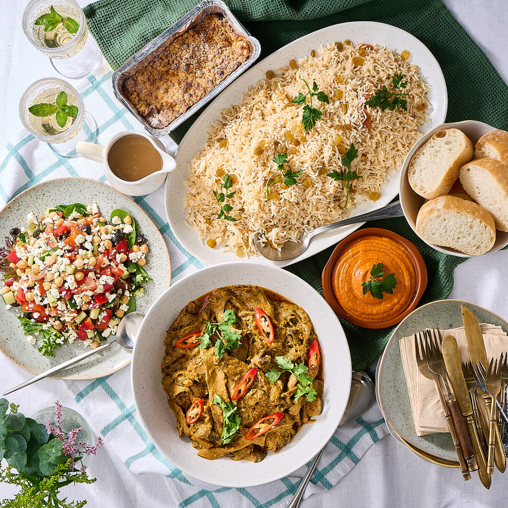 Vegetarian mini buffet spread from above: mushroom curry, pilaf, chickpea salad, muhammara, bread and a sauce jug