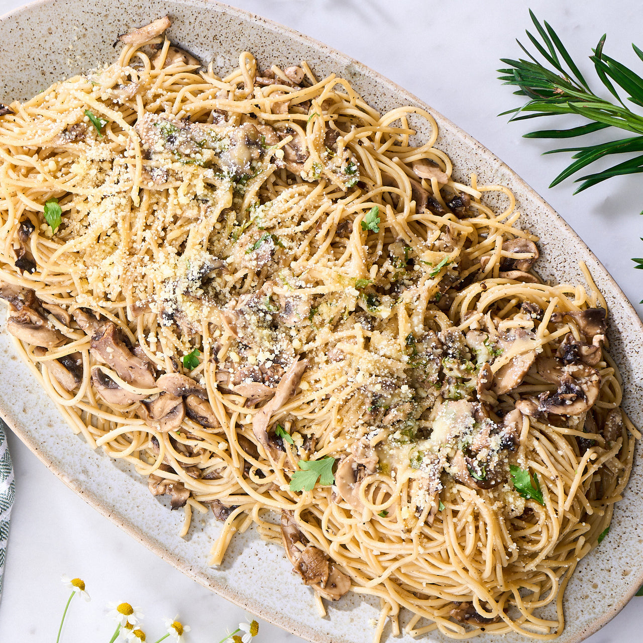 Aglio Olio spaghetti with mushrooms garnished with vegan cheese