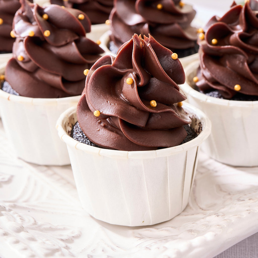 Close-up of chocolate ganache piped into tree swirls and dotted with gold pearls
