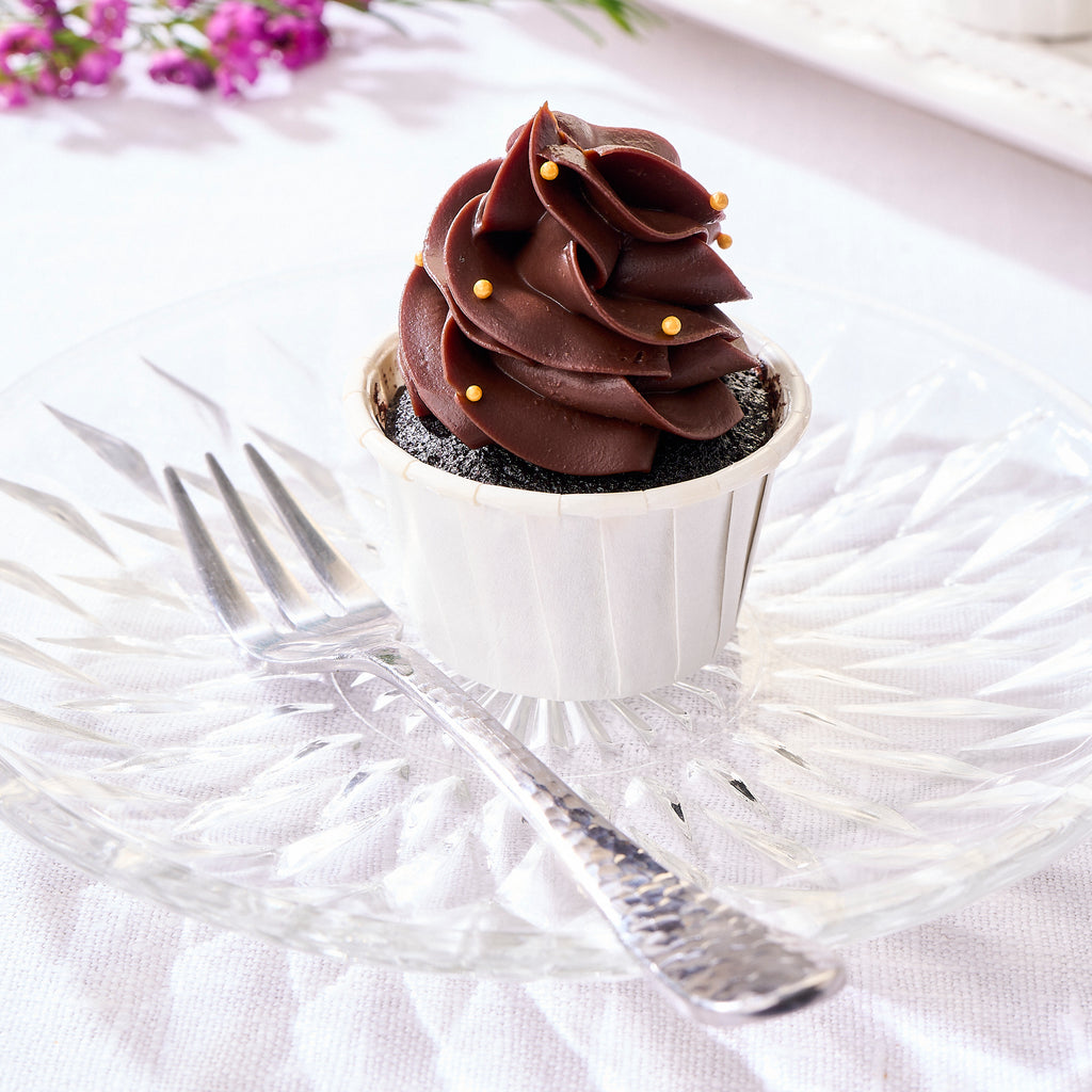 A single chocolate tree cupcake in a white case on a cut-glass plate with a fork