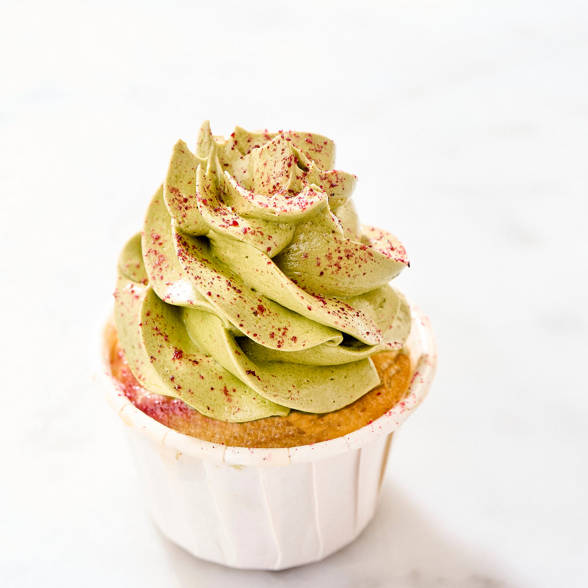 Close-up of matcha cream piped into a tree and speckled with raspberry powder