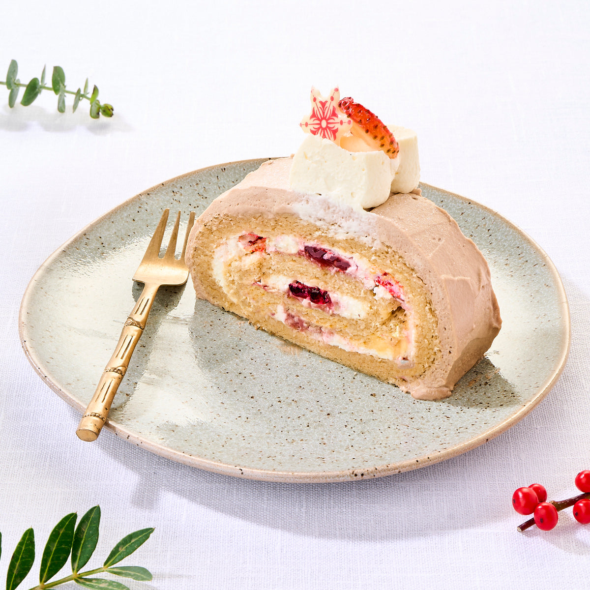 A slice of Christmas log cake showing bergamot sponge rolled with cream and berry jam