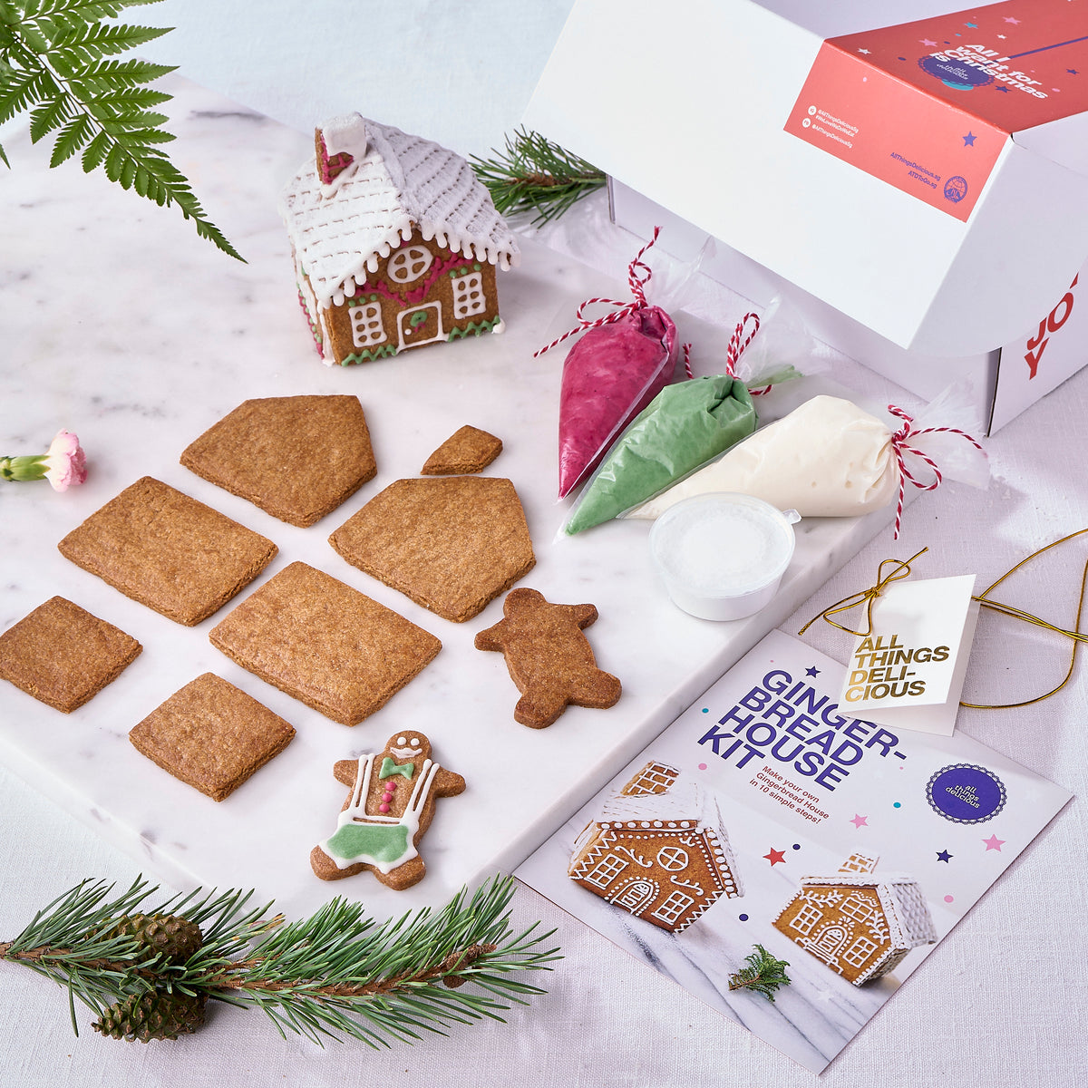 Christmas gingerbread house kit laid out with panels, icing bags and snow powder