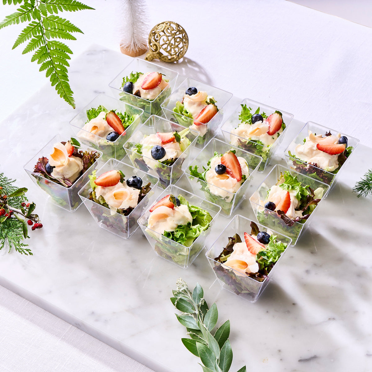 Twelve Christmas salad cups with lychee turkey, greens, strawberries and blueberries