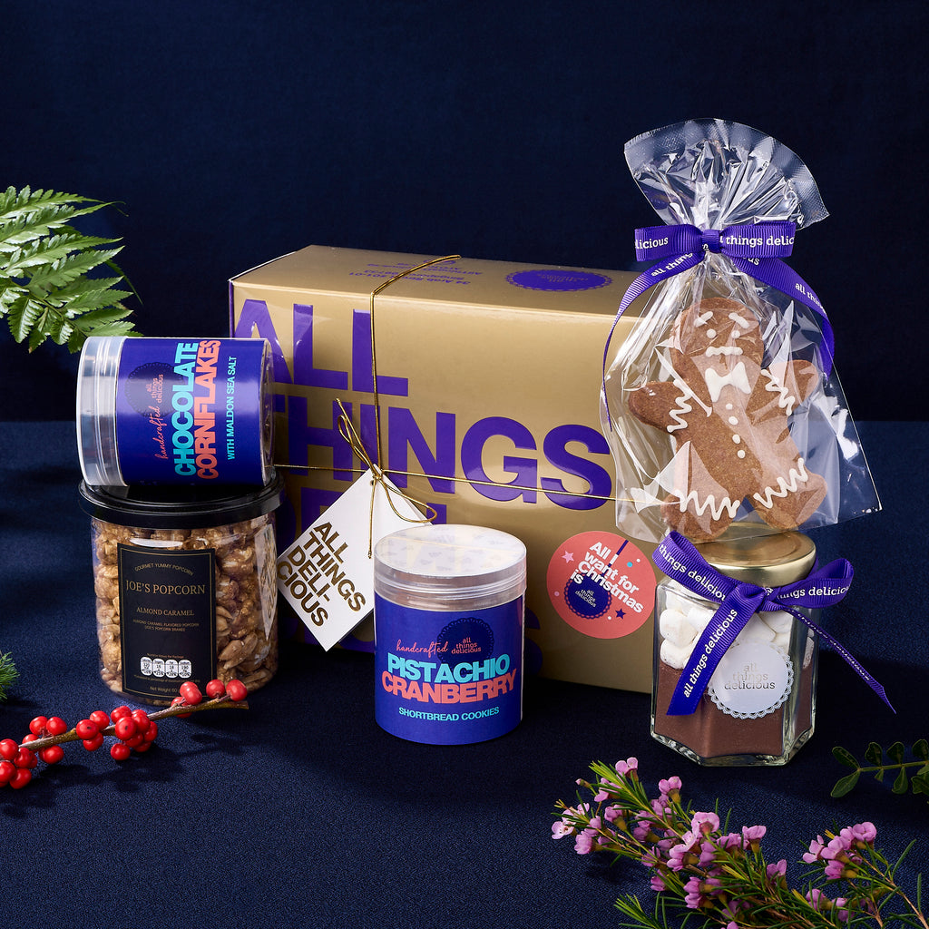 Gold gift box with mini cookie jars, almond caramel popcorn and a gingerbread man