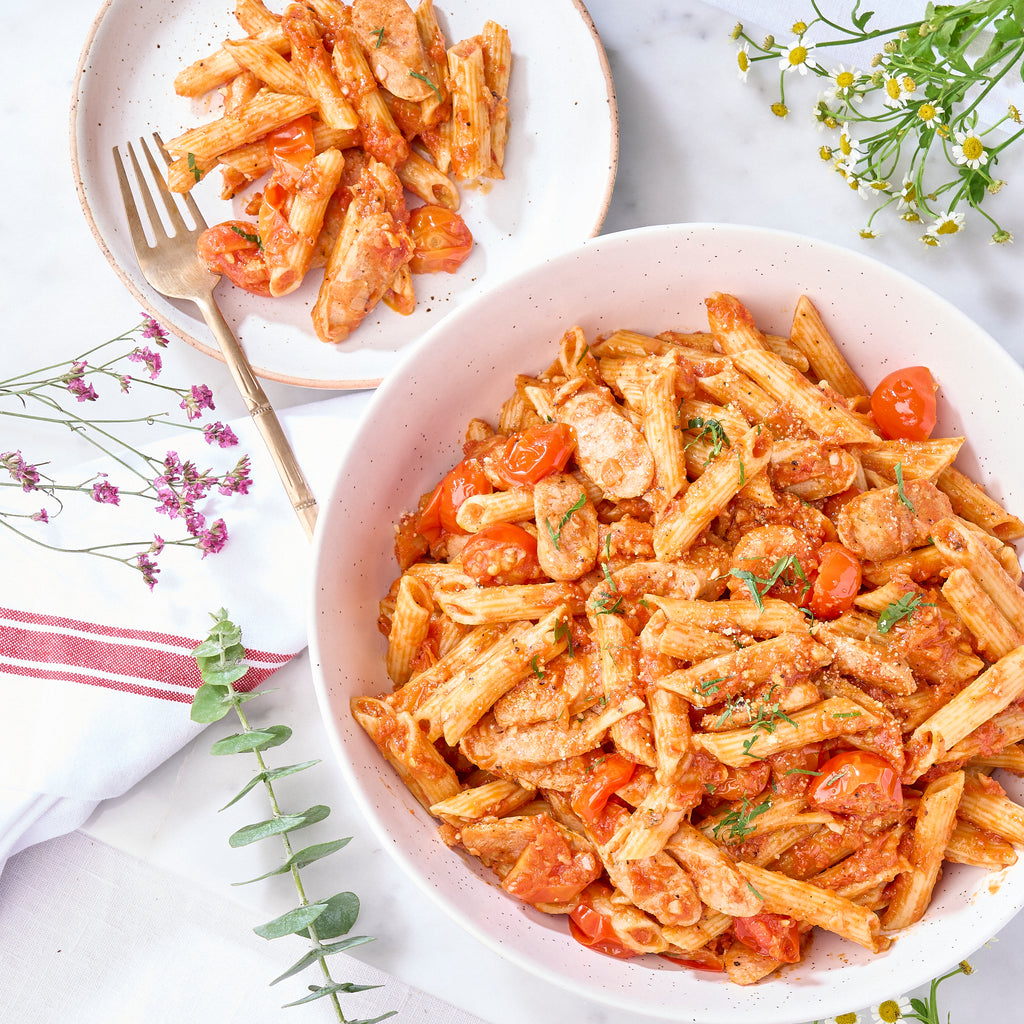 Fennel sausage and cherry tomato penne in a serving bowl with a plated portion, a halal pasta for sharing
