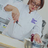 Pastry chef rolling and coating the Earl Grey Strawberry log cake
