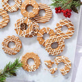 Gingerbread wreath cookies decorated with white icing and sprinkles, alongside Christmas decorations.